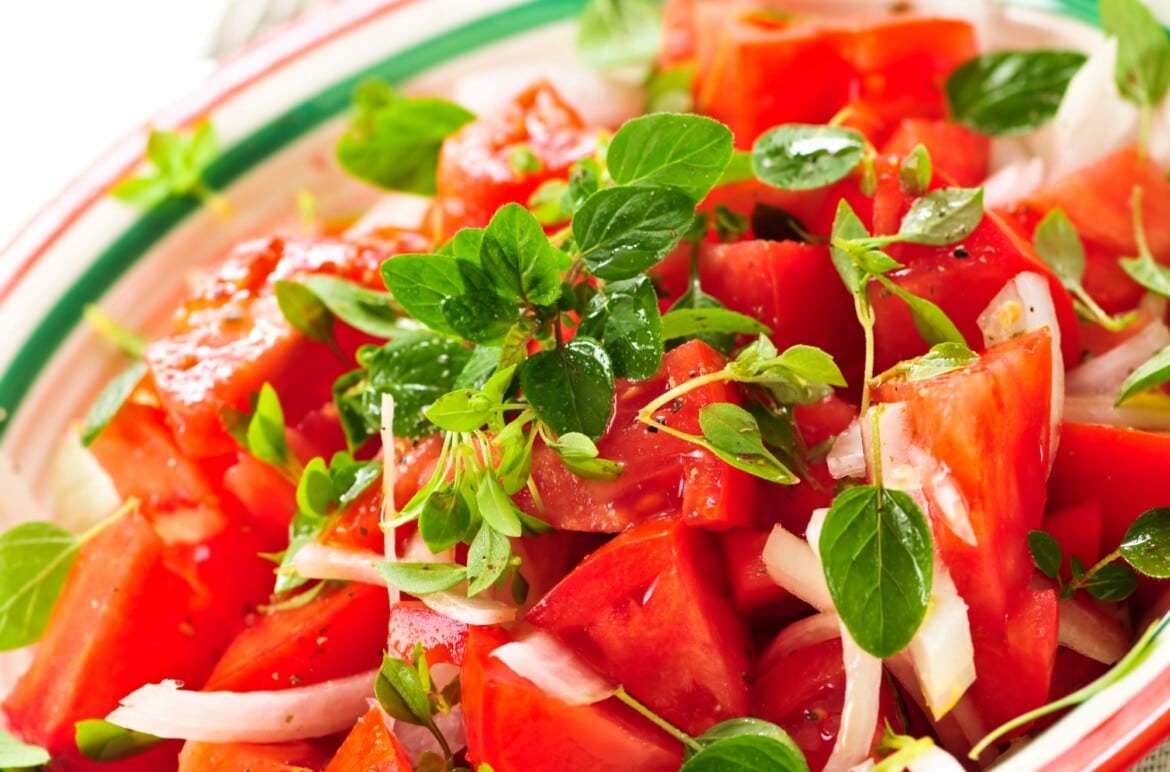 Tuscan tomato salad with slices onions and green leaves